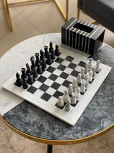 Marble chessboard with black and white chess pieces on a round marble table.