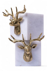 Gold deer head earrings on a white card with a marble background