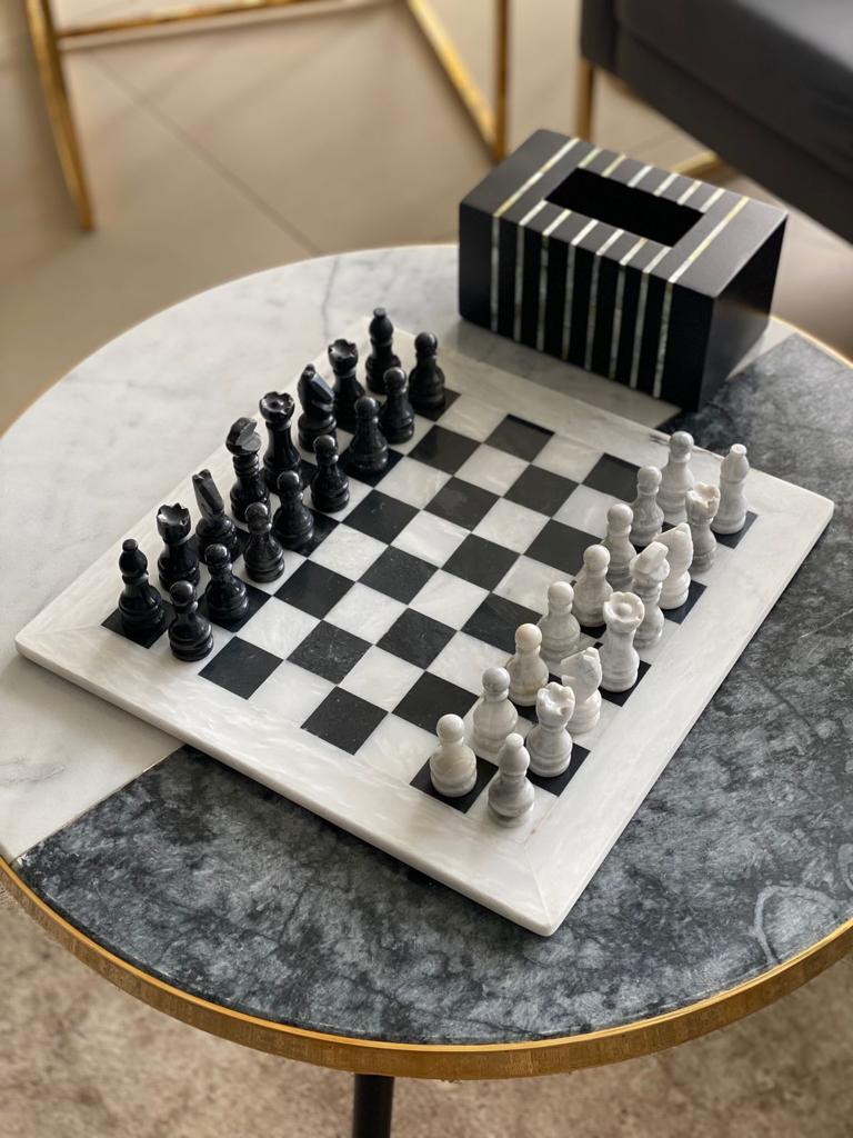 Marble chessboard with black and white chess pieces on a round marble table.