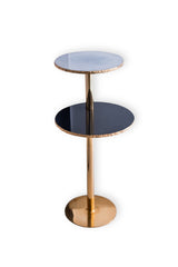 Two-tiered side table with gold base and black and blue glass tops on a white background