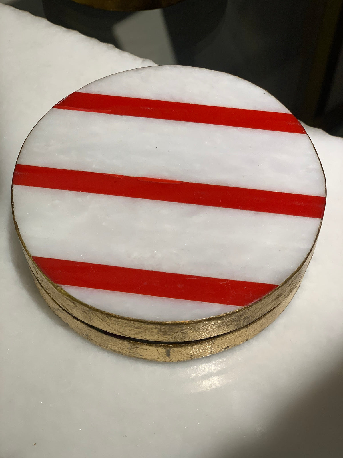 Round object with red and white striped pattern on a white background