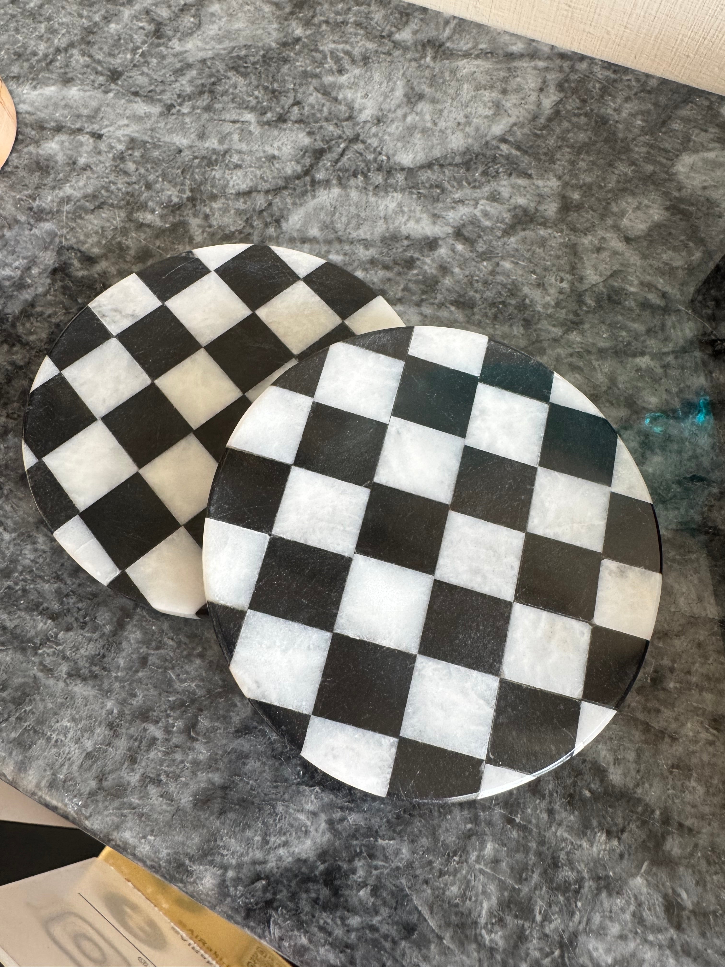 Two black and white checkered coasters on a gray surface