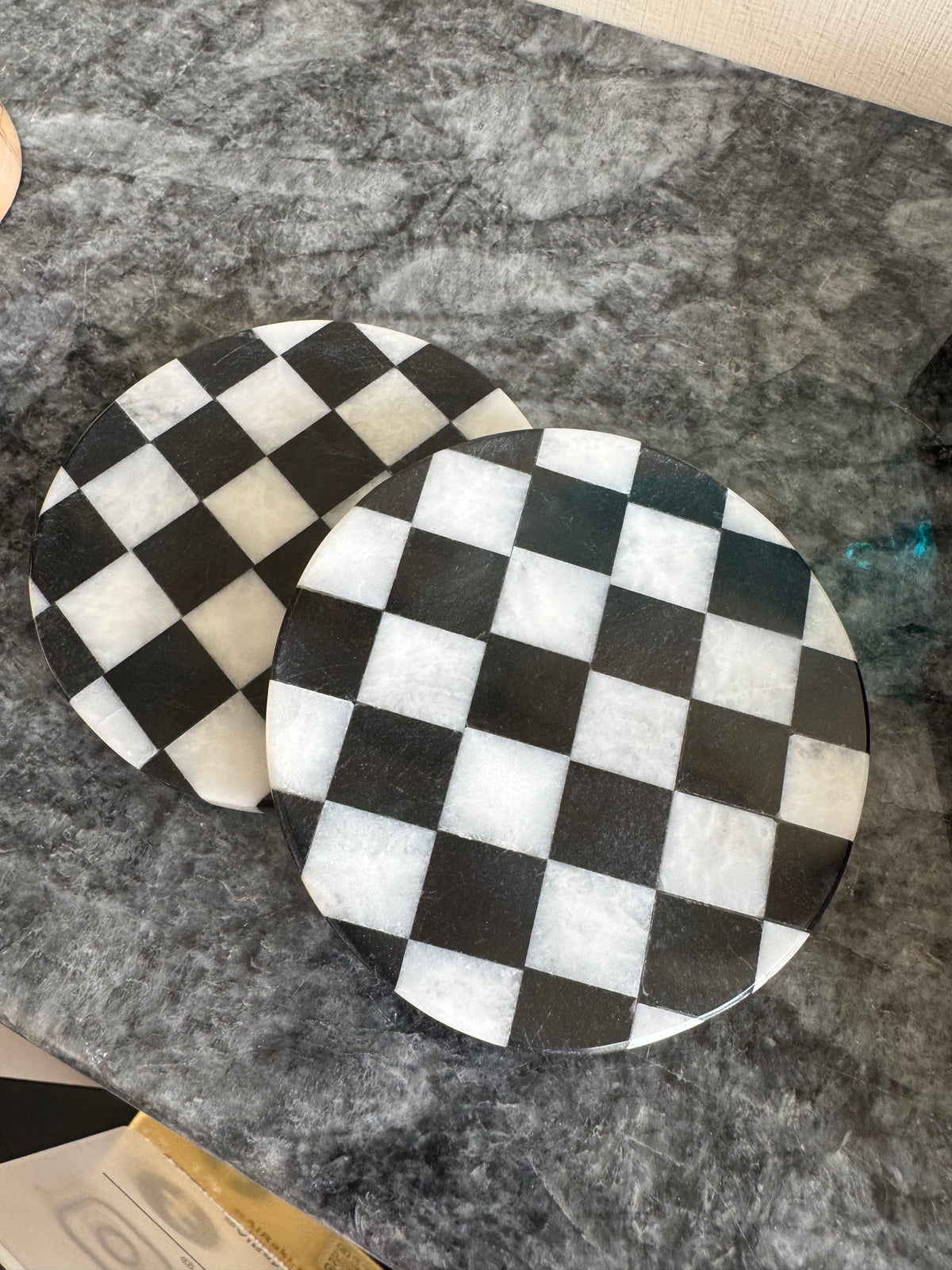 Two black and white checkered coasters on a gray surface