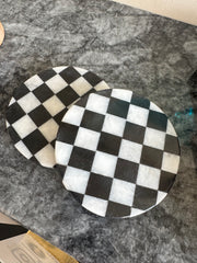 Two black and white checkered coasters on a gray surface
