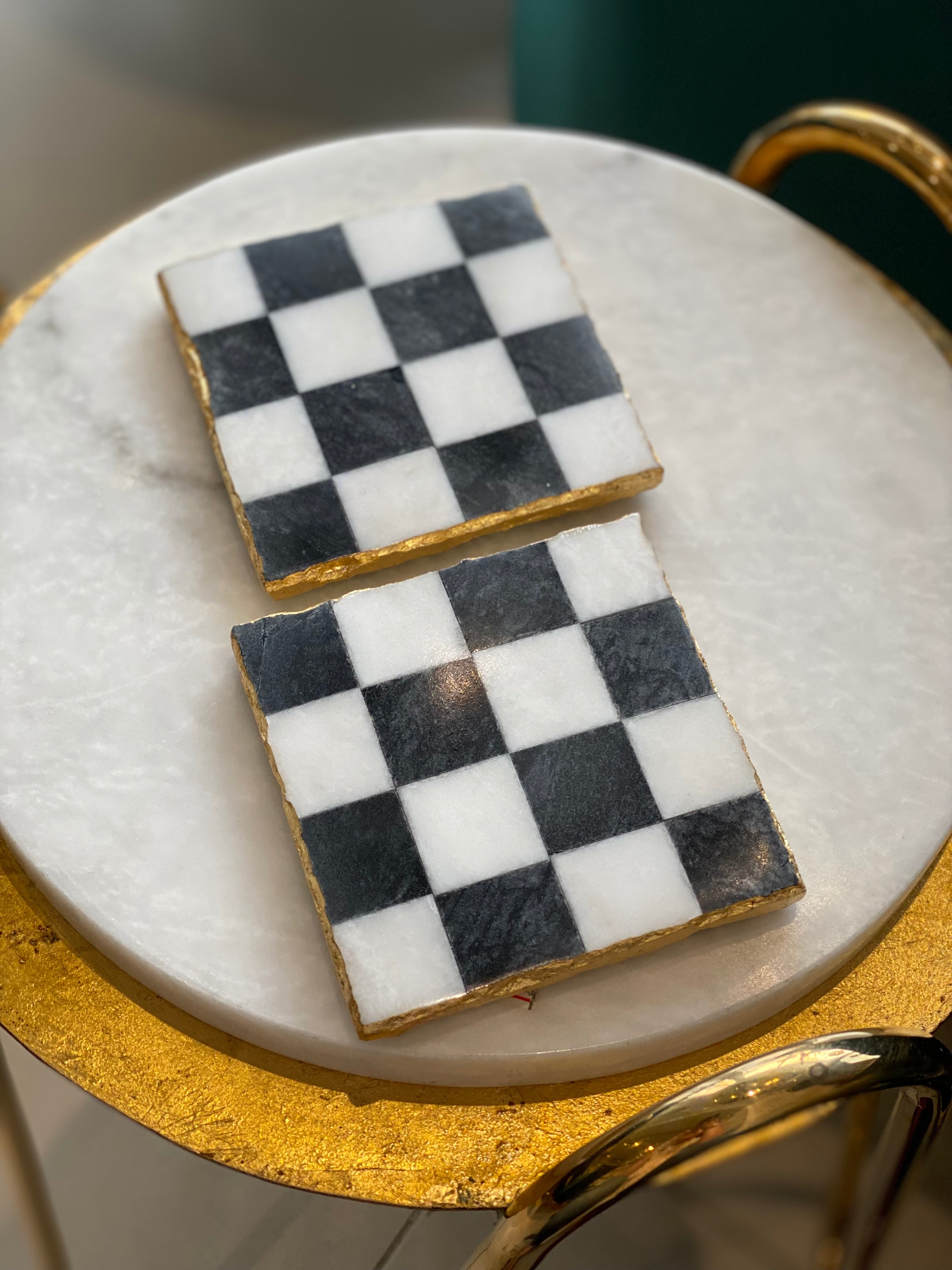 Two checkered cookies on a marble surface with gold trim