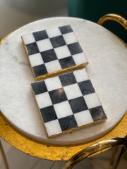 Two checkered cookies on a marble surface with gold trim