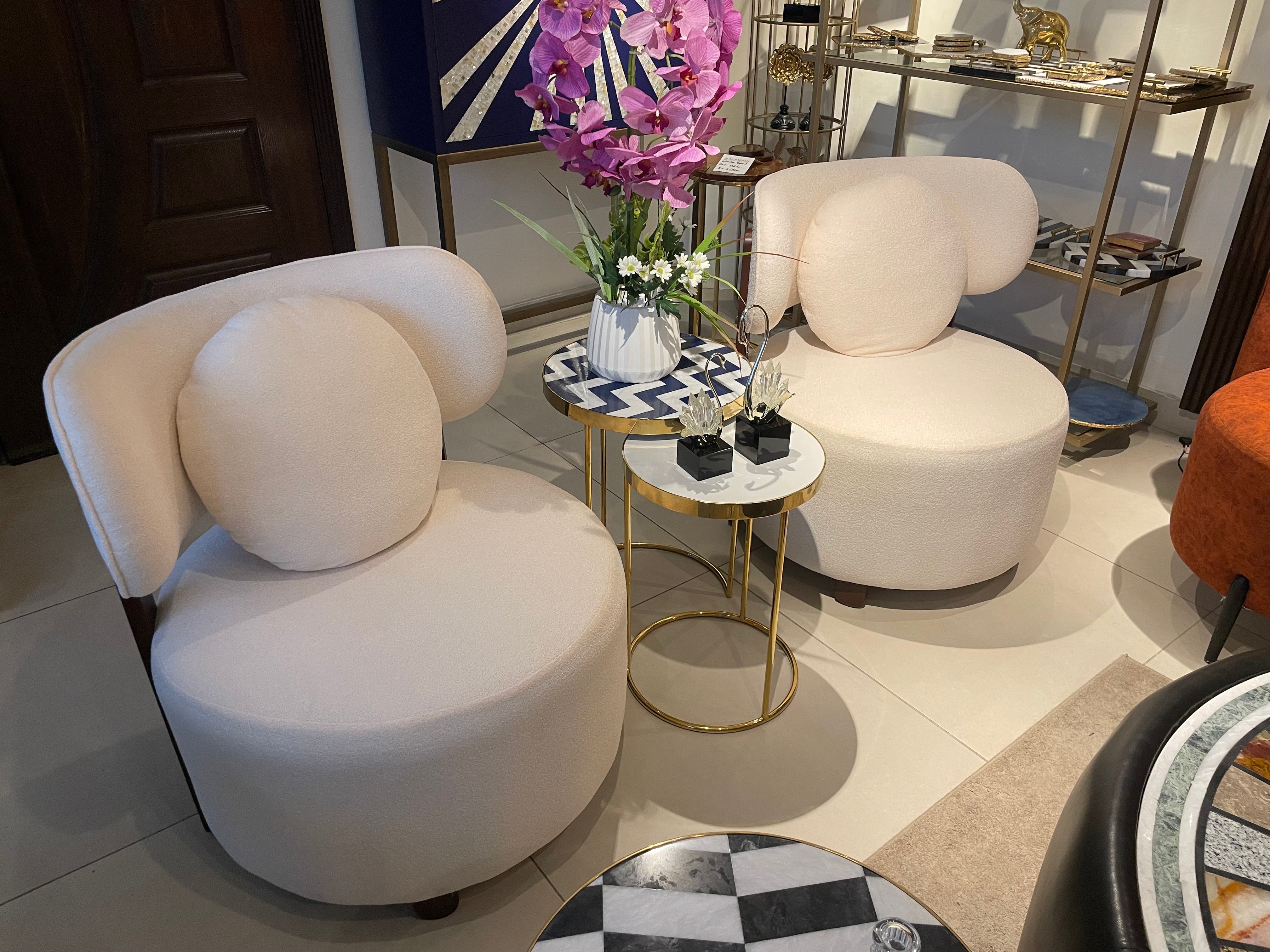 Modern living room with white curved chairs, small round table, and decorative items.