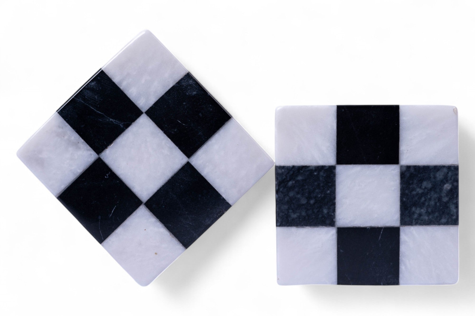 Two square marble coasters with black and white checkered pattern on a white background