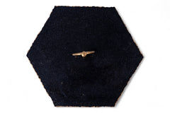 Gold airplane-shaped brooch on a black hexagonal fabric background