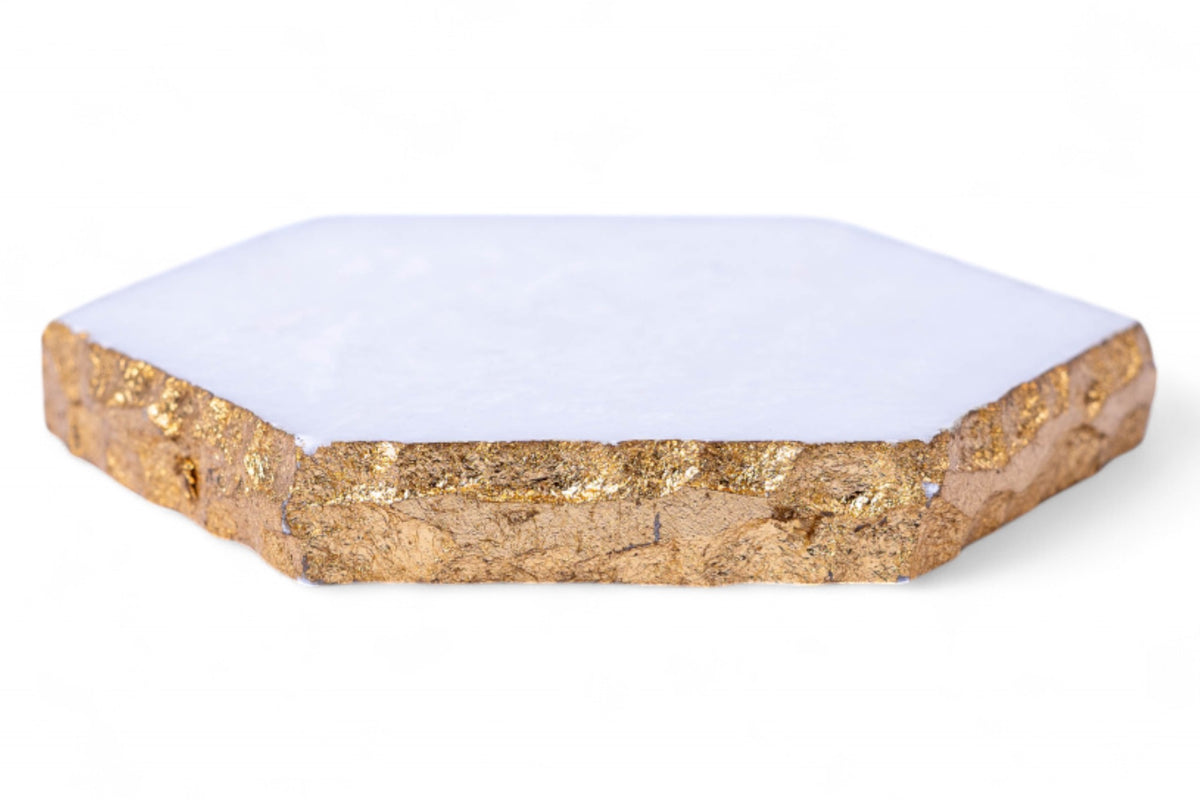 Hexagonal white coaster with gold edge on a white background