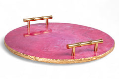 Pink round tray with gold edges and handles on a white background