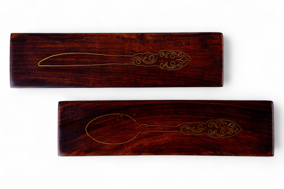 Two wooden spoons in engraved wooden holders on a white background