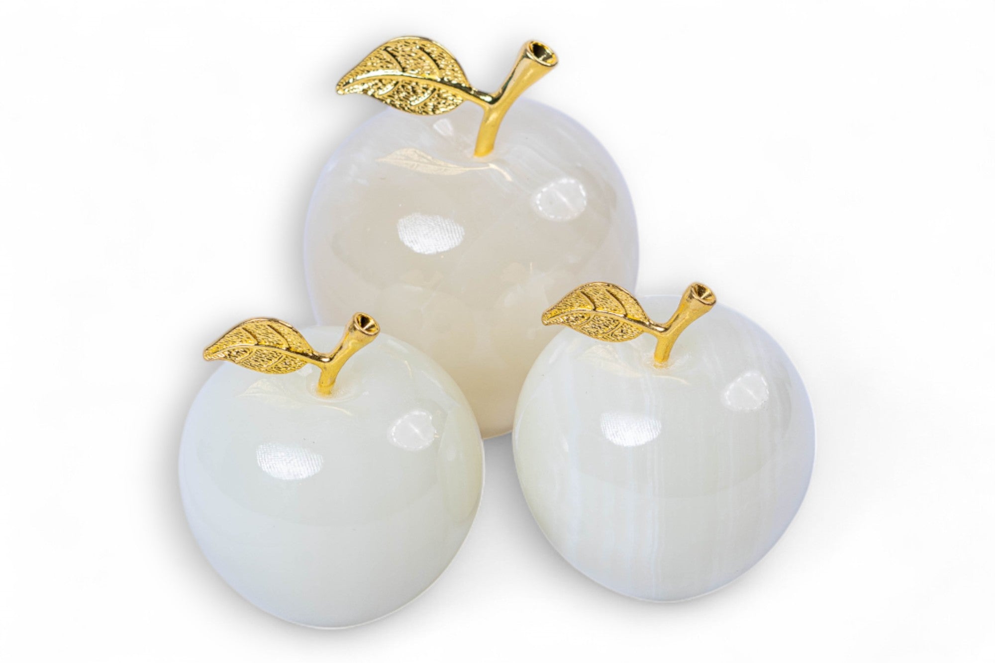 Three white stone apples with gold leaves on a white background