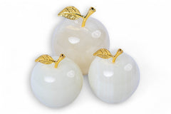 Three white stone apples with gold leaves on a white background