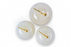 Three white spherical objects with gold pins on a white background