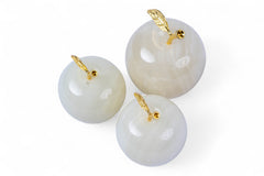 Three white spherical objects with gold hooks on a white background