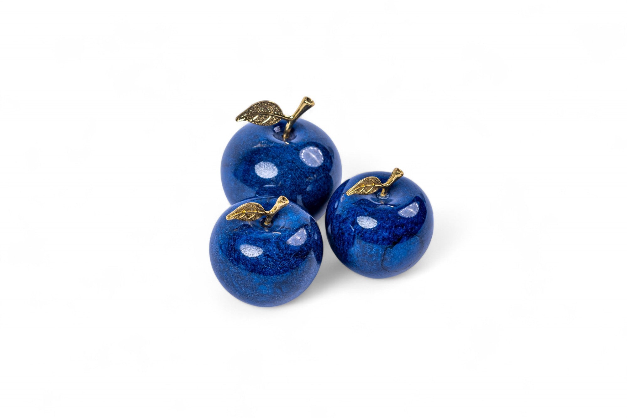 Three blue decorative apples with gold leaves on a white background