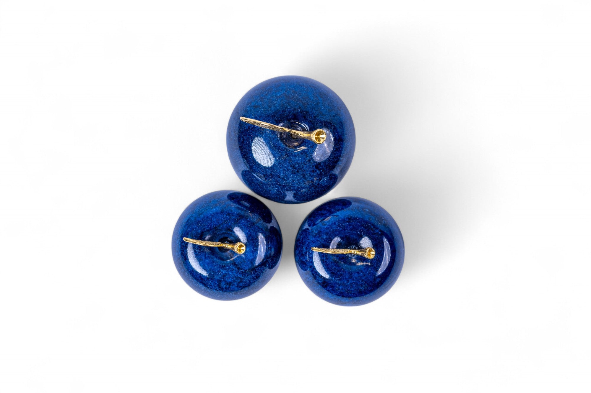Three blue spherical objects with gold accents on a white background