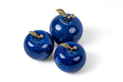 Three blue decorative apples with gold leaves on a white background
