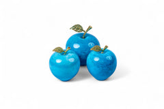 Three blue decorative apples with gold stems on a white background