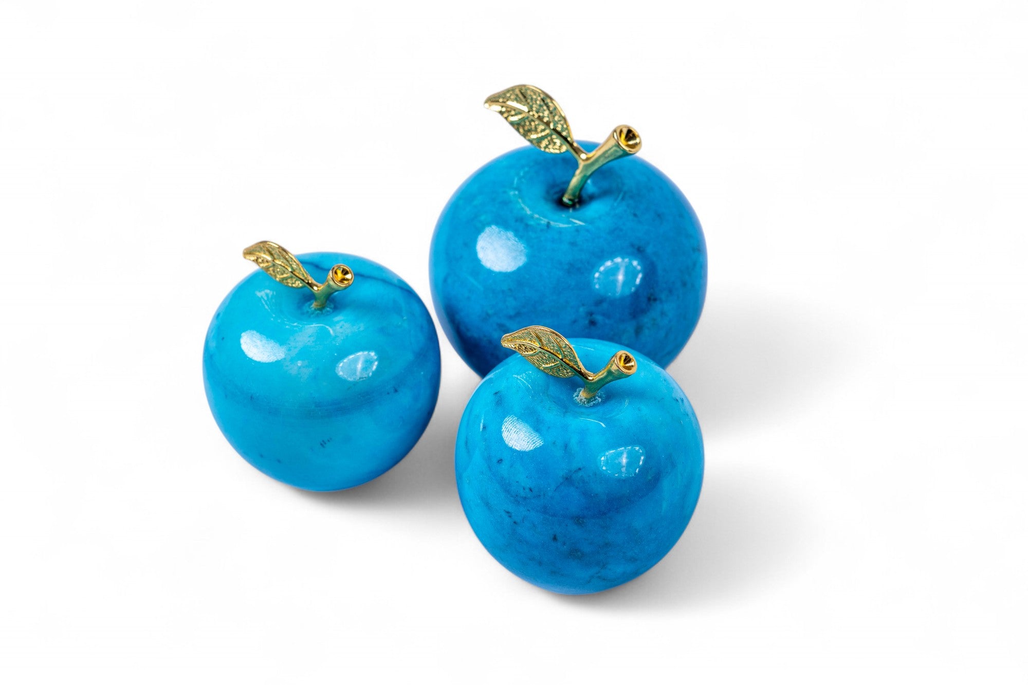 Three blue apples with gold stems on a white background