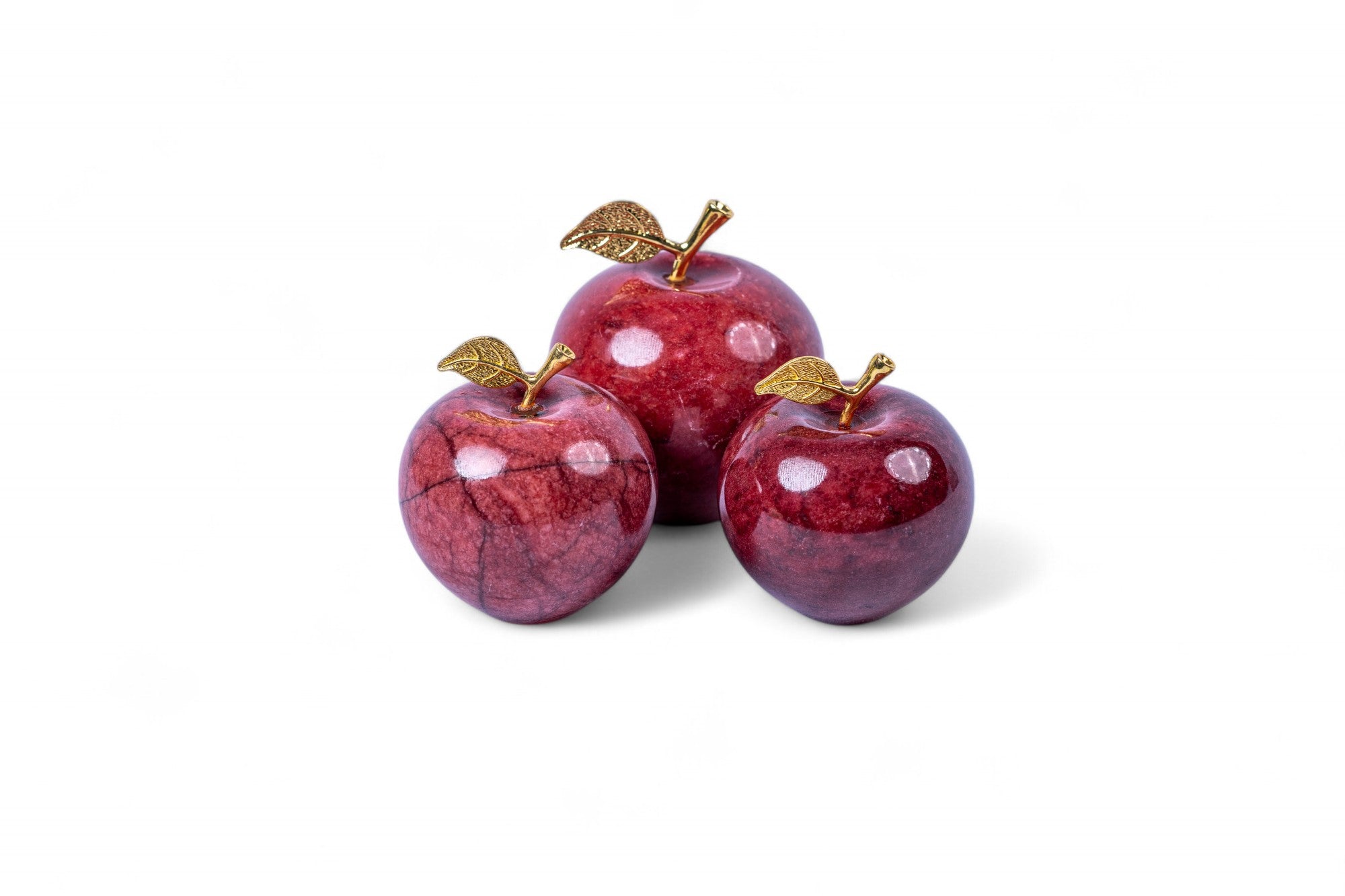 Three decorative red apples with gold leaves on a white background