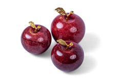 Three decorative red apples with gold stems on a white background