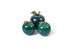 Three green stone apples with gold leaves on a white background