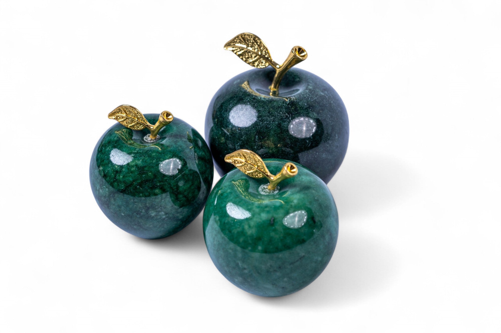 Three decorative apples with gold leaves on a white background