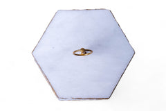 Hexagonal white jewelry box with a gold ring on a white background