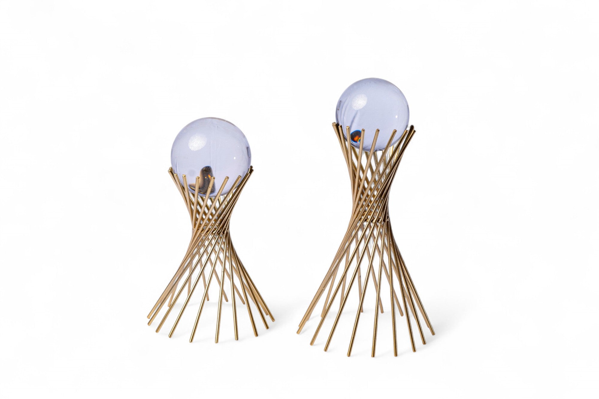 Pair of earrings with spherical purple gemstones and wavy gold base on a white background