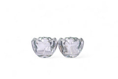 Two clear glass lotus-shaped candle holders on a white background