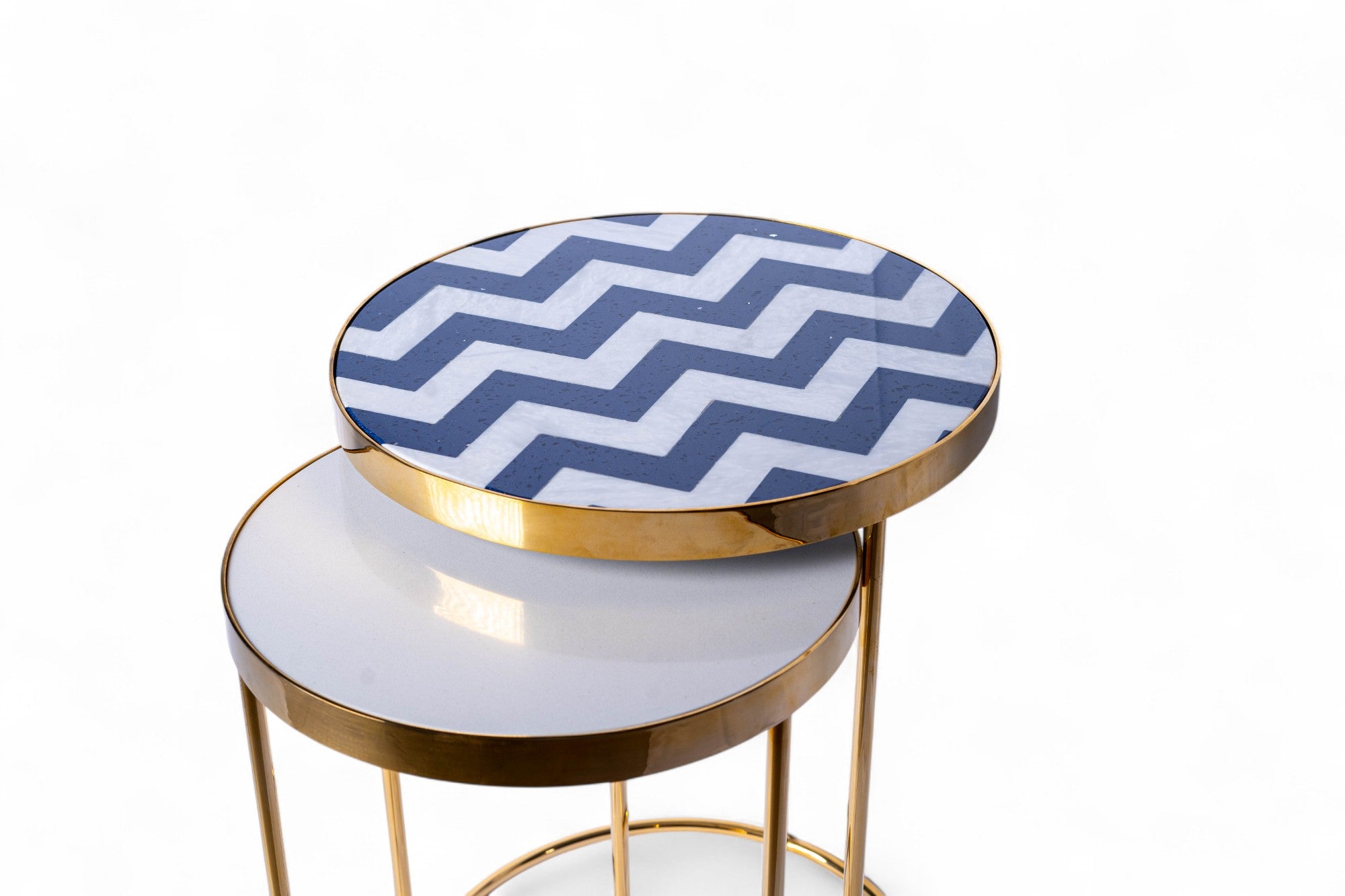Round side table with gold frame and blue and white zigzag patterned top on a white background