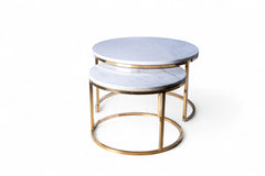 Set of two round marble tables with gold metal bases on a white background