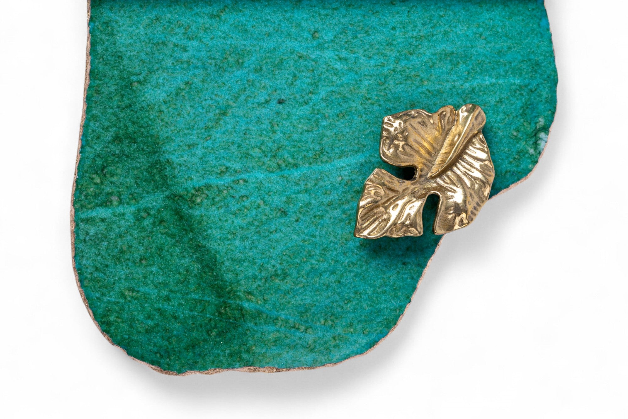 Gold leaf-shaped brooch on a turquoise stone background