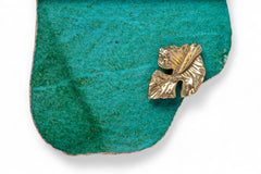 Gold leaf-shaped brooch on a turquoise stone background