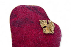 Gold leaf-shaped brooch on a textured red fabric background