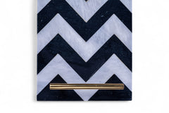 Notebook with black and white chevron pattern cover and gold pen on a white background