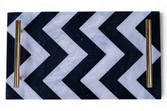 Black and white chevron patterned tray with gold handles on a white background