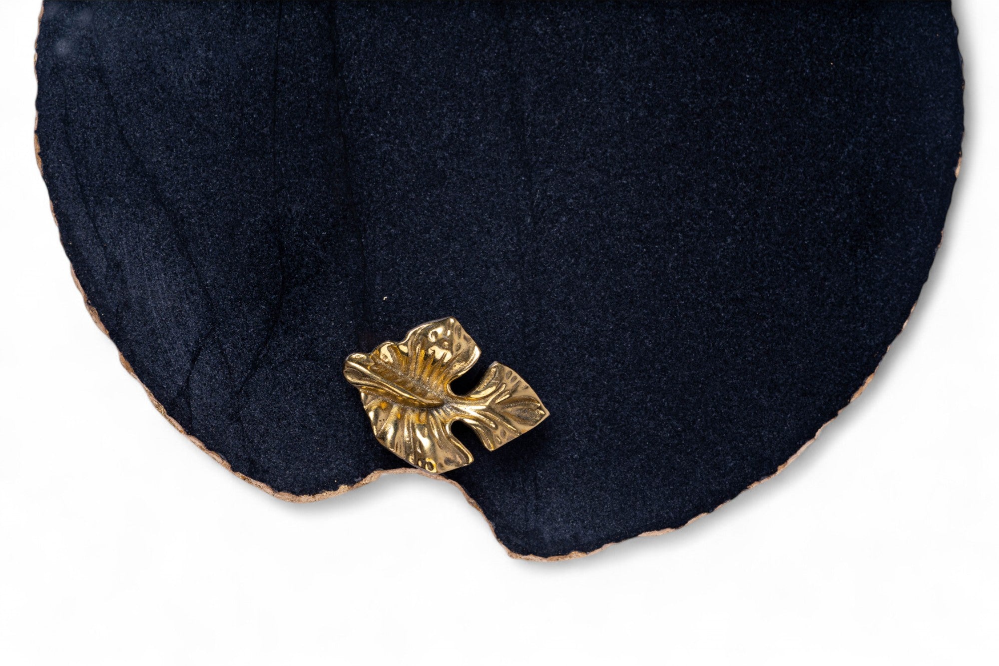 Gold leaf-shaped earring on a dark blue fabric background