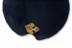 Gold leaf-shaped earring on a dark blue fabric background