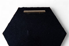 Black hexagonal object with a gold bar on a white background