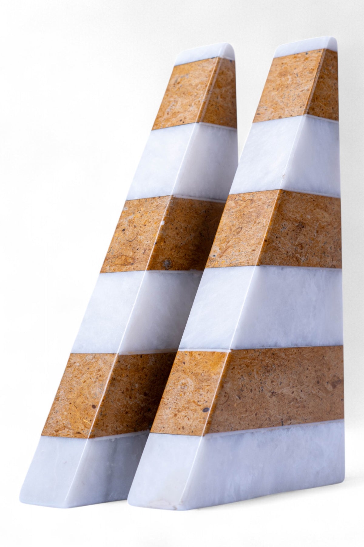 Three geometric stone blocks with striped pattern on a white background