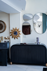 Modern interior with a black console table, decorative mirrors, and wall art.
