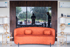 Orange sofa in a modern living room with a large TV screen displaying an outdoor scene.