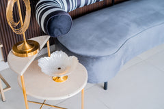Decorative bowl on a side table with a gold lamp and striped cushion in the background
