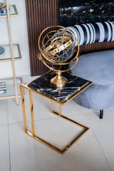 Decorative gold sphere on a black marble side table with a striped cushion in the background.