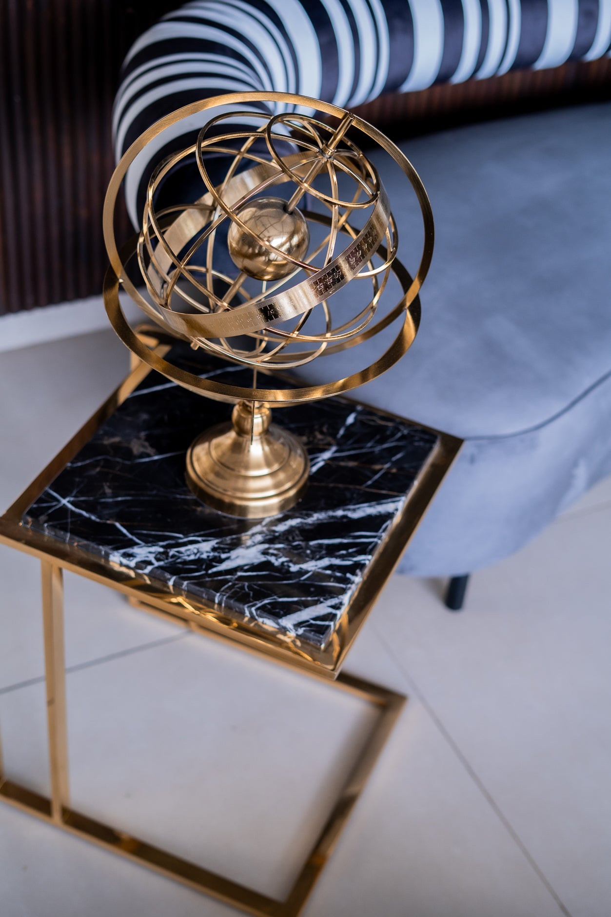 Gold spherical decorative object on a marble table with a blurred background
