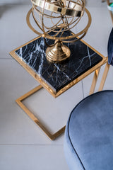 Gold and black marble side table with a blue stool in the foreground