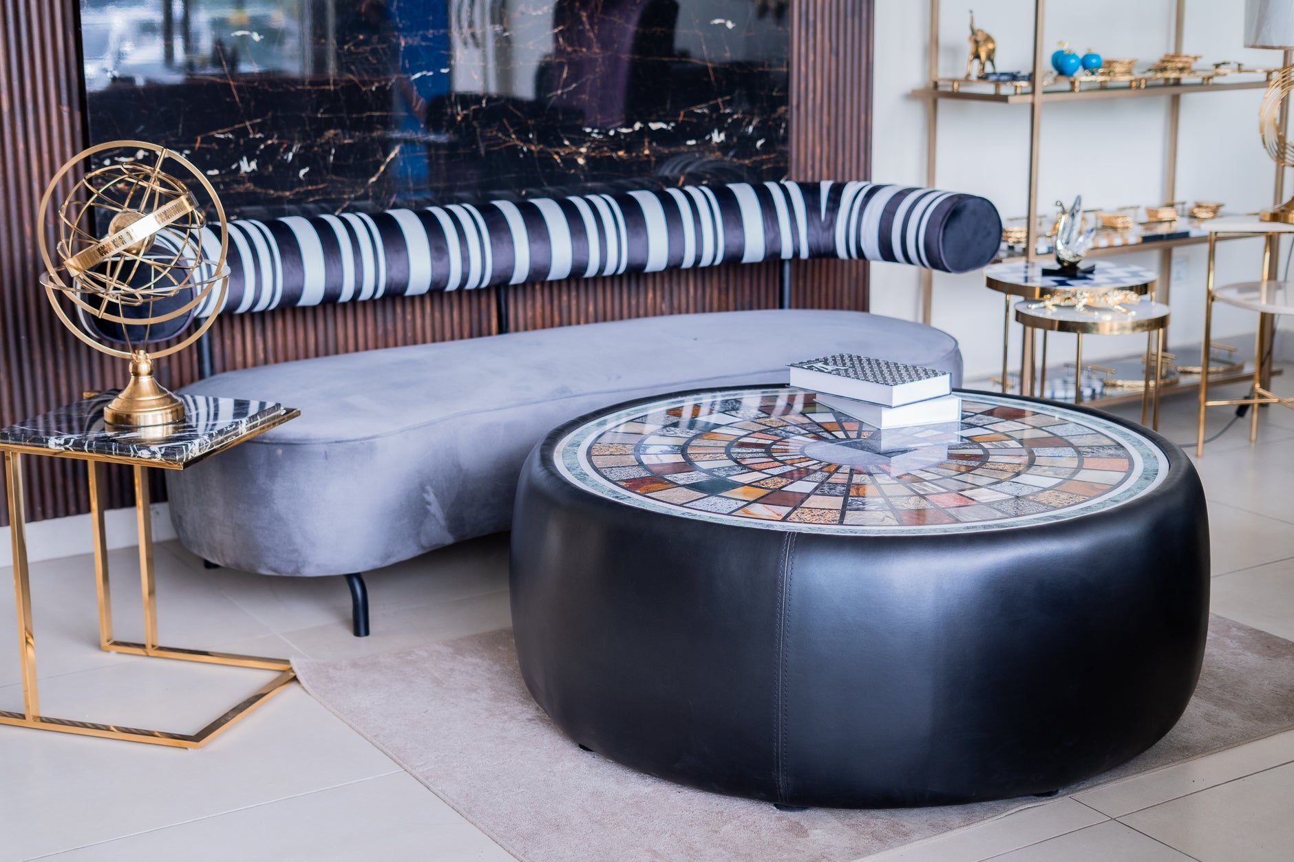 Modern living room with a round black coffee table, gray sofa, and decorative items.